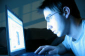 Image of man looking at a computer in the dark.